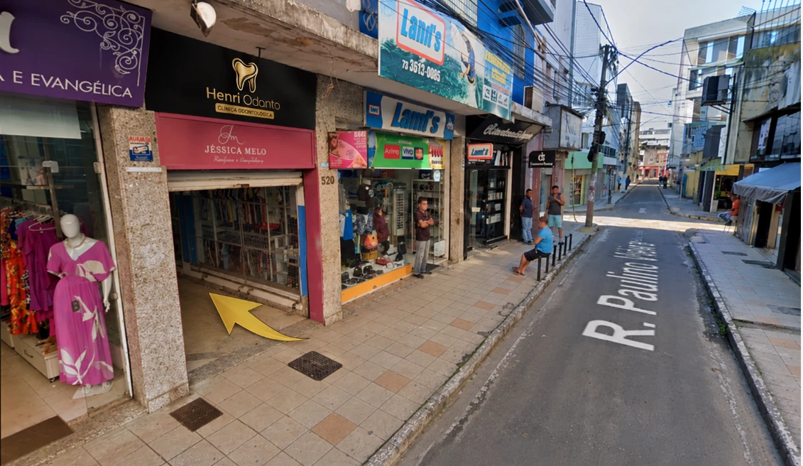 Fachada da Henri Odonto na Rua Paulino Vieira, no Centro de Itabuna, com uma seta amarela indicando a entrada